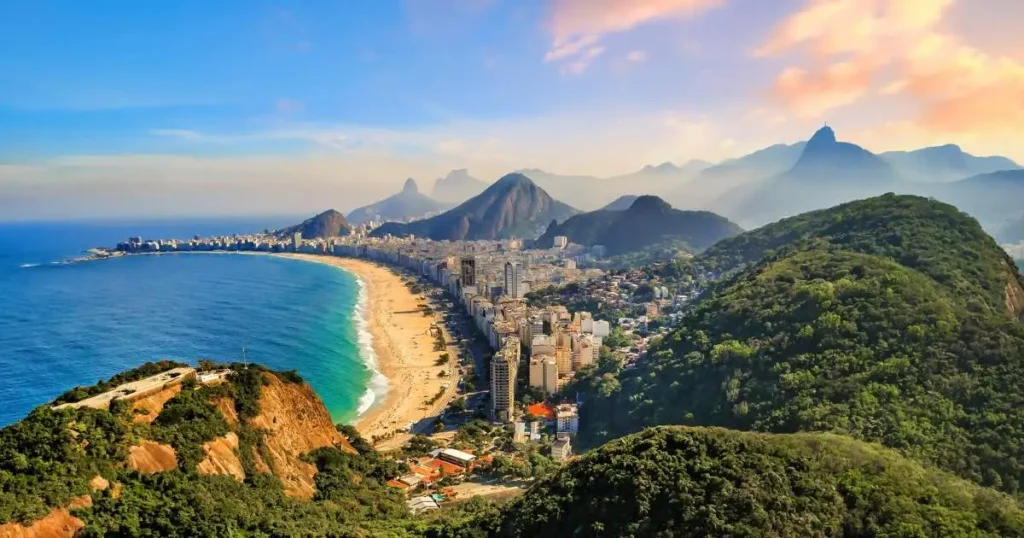 A stunning aerial view of a beach and cityscape in Brazil, surrounded by lush green mountains – one of the best places to travel with friends in Brazil.